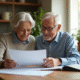 Couple souriant examinant des papiers de retraite à la maison
