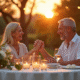 Couple d'âge moyen riant lors d'un dîner d'anniversaire en plein air au coucher du soleil